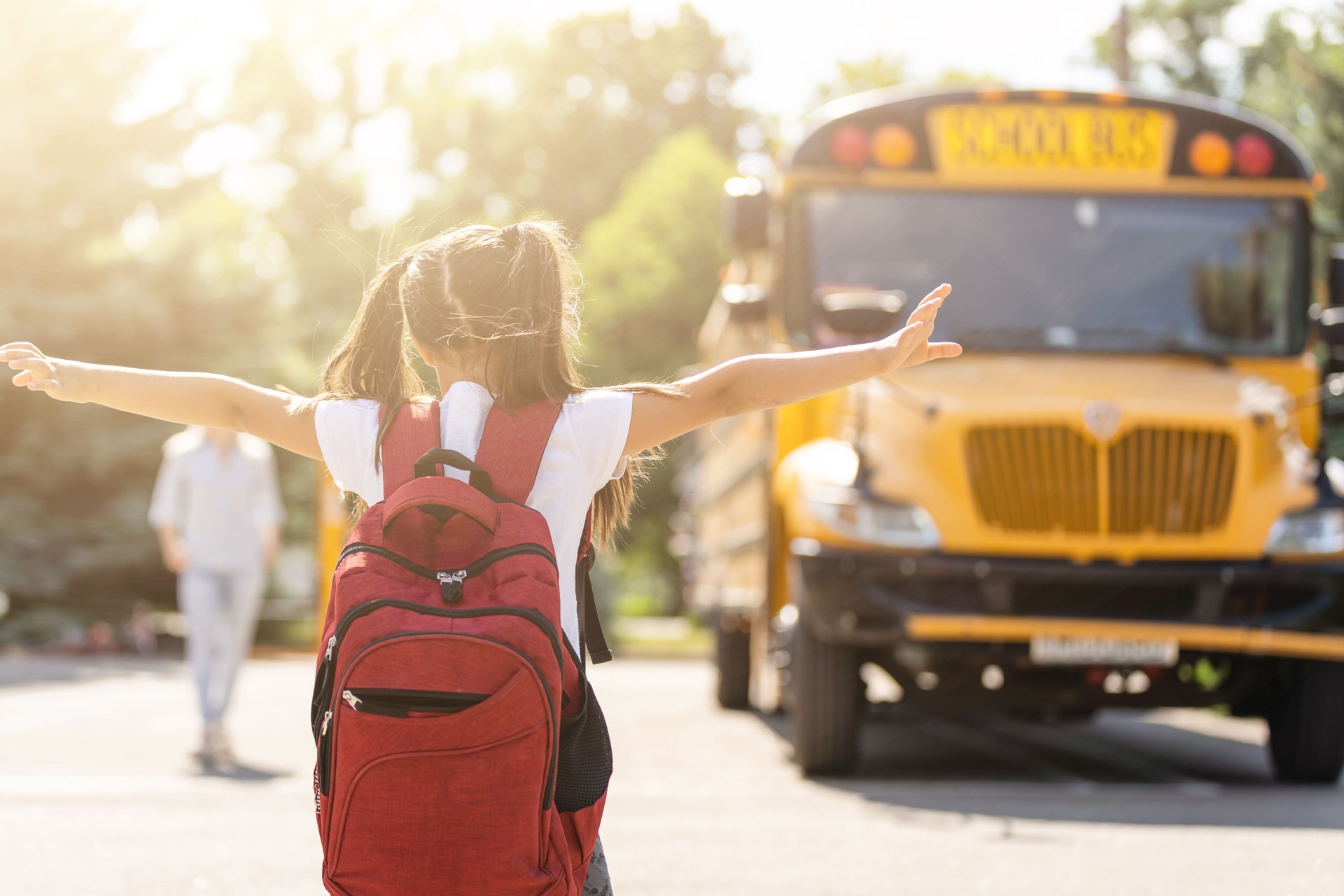 Mother brings her daughter to school near the school bus. back to school